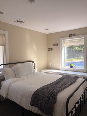 A bedroom with a bed, a window with a view, and a wall with 'Thankful' signs.
