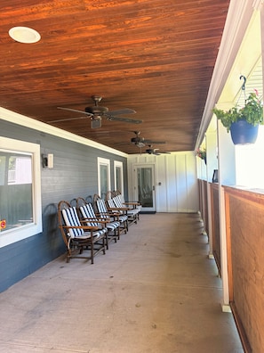 A covered outdoor seating area with ceiling fans, a row of striped chairs, and a concrete floor.