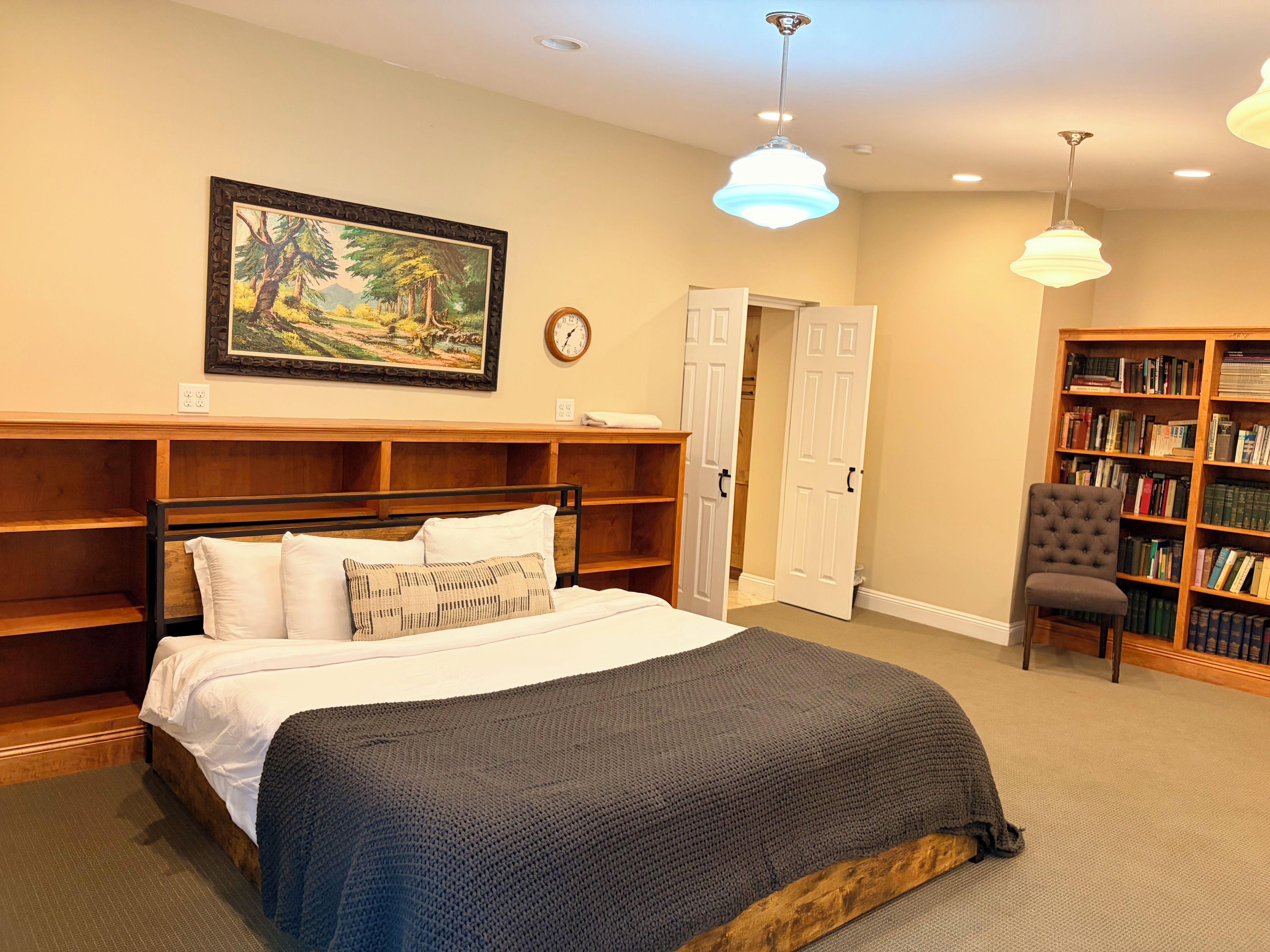 Une chambre à coucher avec un lit, une bibliothèque, une chaise et un tableau accroché au mur.