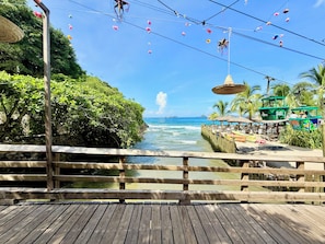 A wooden deck overlooking a coastal area with a view of the ocean and a pier with seating. - Vista Pacífico • Beachfront Condo • Pool • Ixtapa-Zihuatanejo (Ixtapa Zihuatanejo)