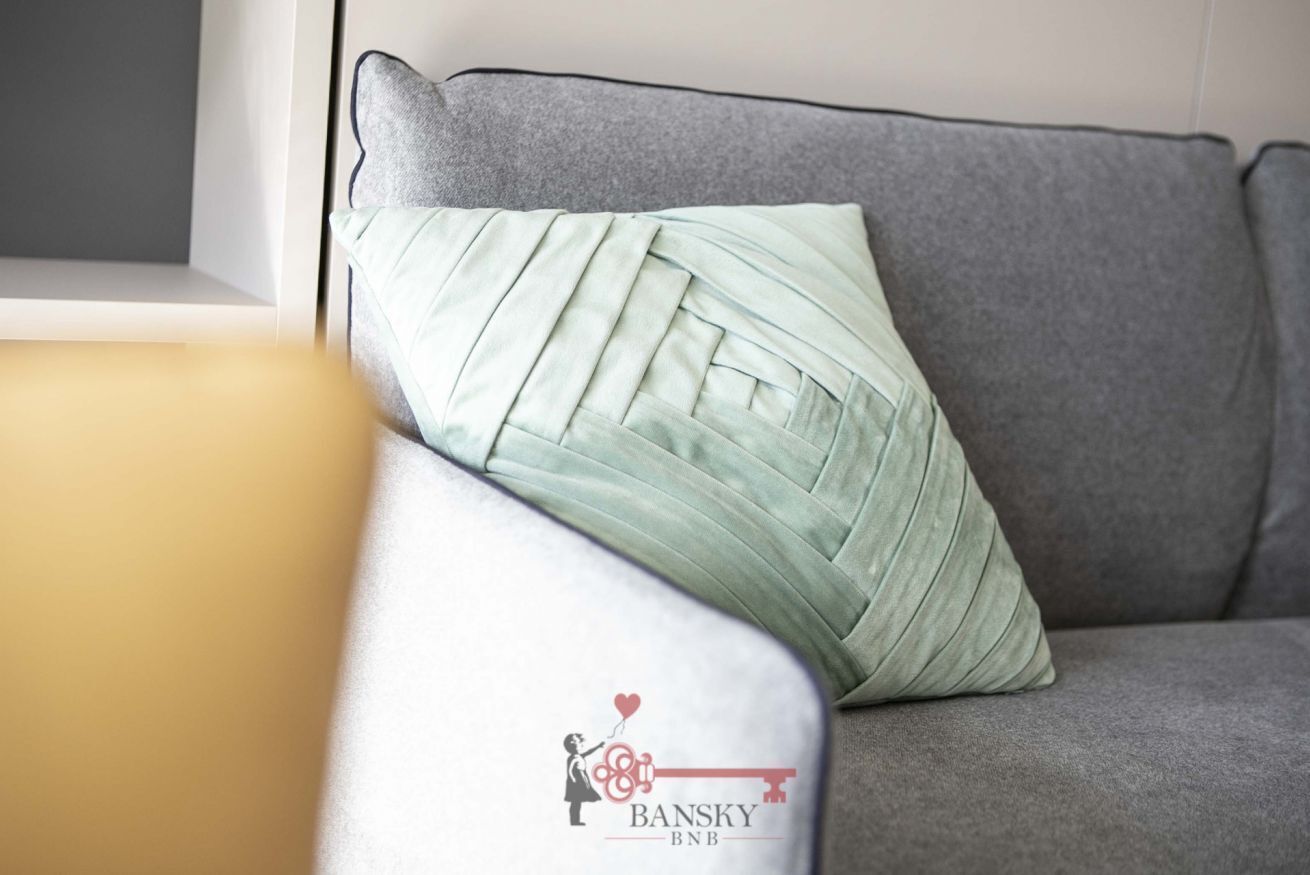 Un canapé gris avec un coussin vert clair.