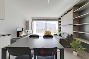 A modern interior with a dining table, chairs, a sofa, and built-in shelving.