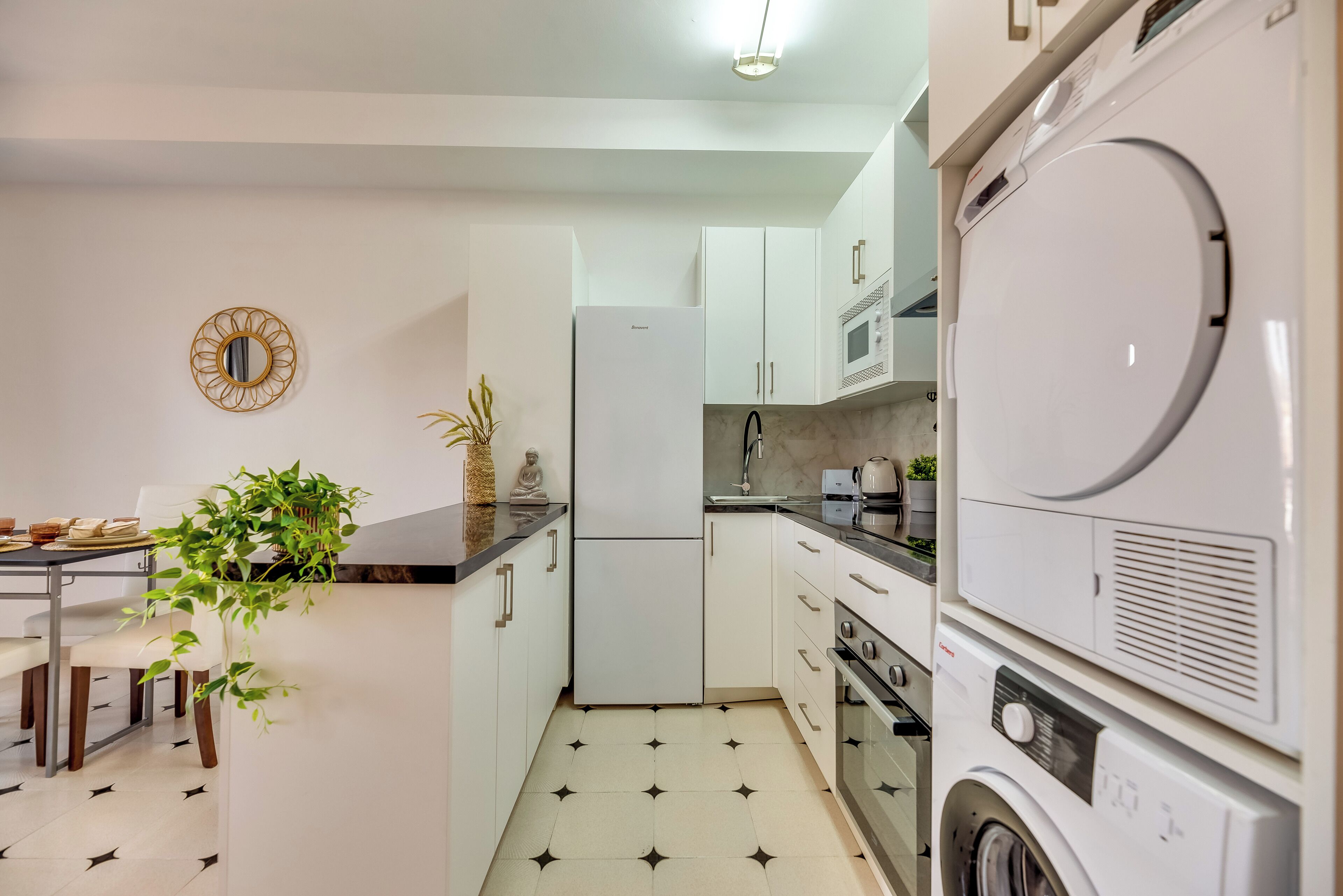 Une cuisine compacte équipée d’un réfrigérateur, d’un four à micro-ondes, d’un four et d’un lave-linge.