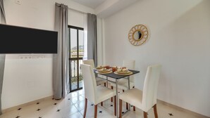Ein Essbereich mit einem Tisch für vier Personen, einem an der Wand montierten Fernseher und einem Balkon mit Blick.