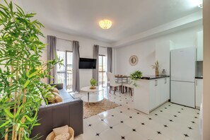 Ein modernes Wohnzimmer mit Sofa, Esstisch und Küchenbereich inklusive Kühlschrank.