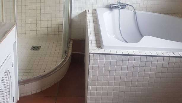 Un baño con cabina de ducha, bañera y paredes con azulejos.