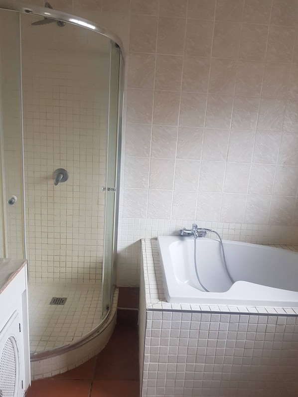 Ein Badezimmer mit Duschkabine, Badewanne und gefliesten Wänden.