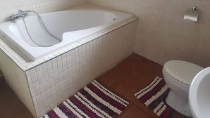 Baño con bañera, inodoro y secamanos.
