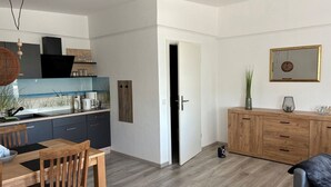Una cocina moderna con comedor, armarios de madera y vista al mar por la ventana.