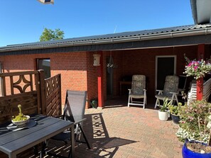 A patio area with a table and chairs, a wooden fence, and potted plants. - Rudi Vacation Rental Near the Baltic Sea with a Natural Garden (Waabs)