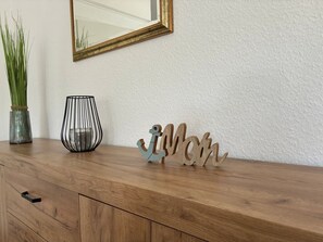 A wooden dresser with a mirror, a vase with green plants, and a black candle holder. - Rudi Vacation Rental Near the Baltic Sea with a Natural Garden (Waabs)
