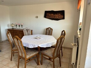 A dining area with a square table, four chairs, a clock, and a decorative piece on the wall. - Rudi Vacation Rental Near the Baltic Sea with a Natural Garden (Waabs)