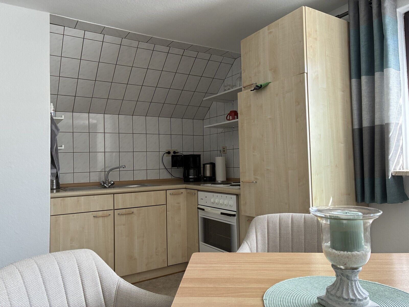 A compact kitchen with a tiled backsplash, a sink, a coffee maker, and a stove.
