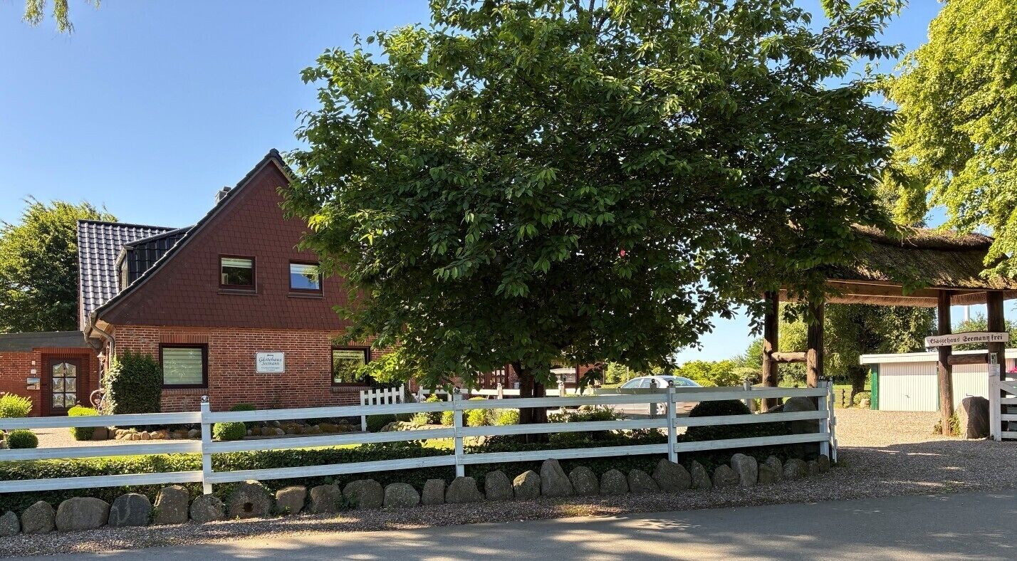 A brick building with a white fence and a large tree in front.