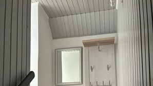 A modern interior with a wooden staircase, a bench, a window, and a door with a handle. - Hans' Vacation Rental Near the Baltic Sea with a Natural Garden (Waabs)