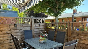 A patio with a table and chairs, a potted plant, and a wooden fence. - Hans' Vacation Rental Near the Baltic Sea with a Natural Garden (Waabs)
