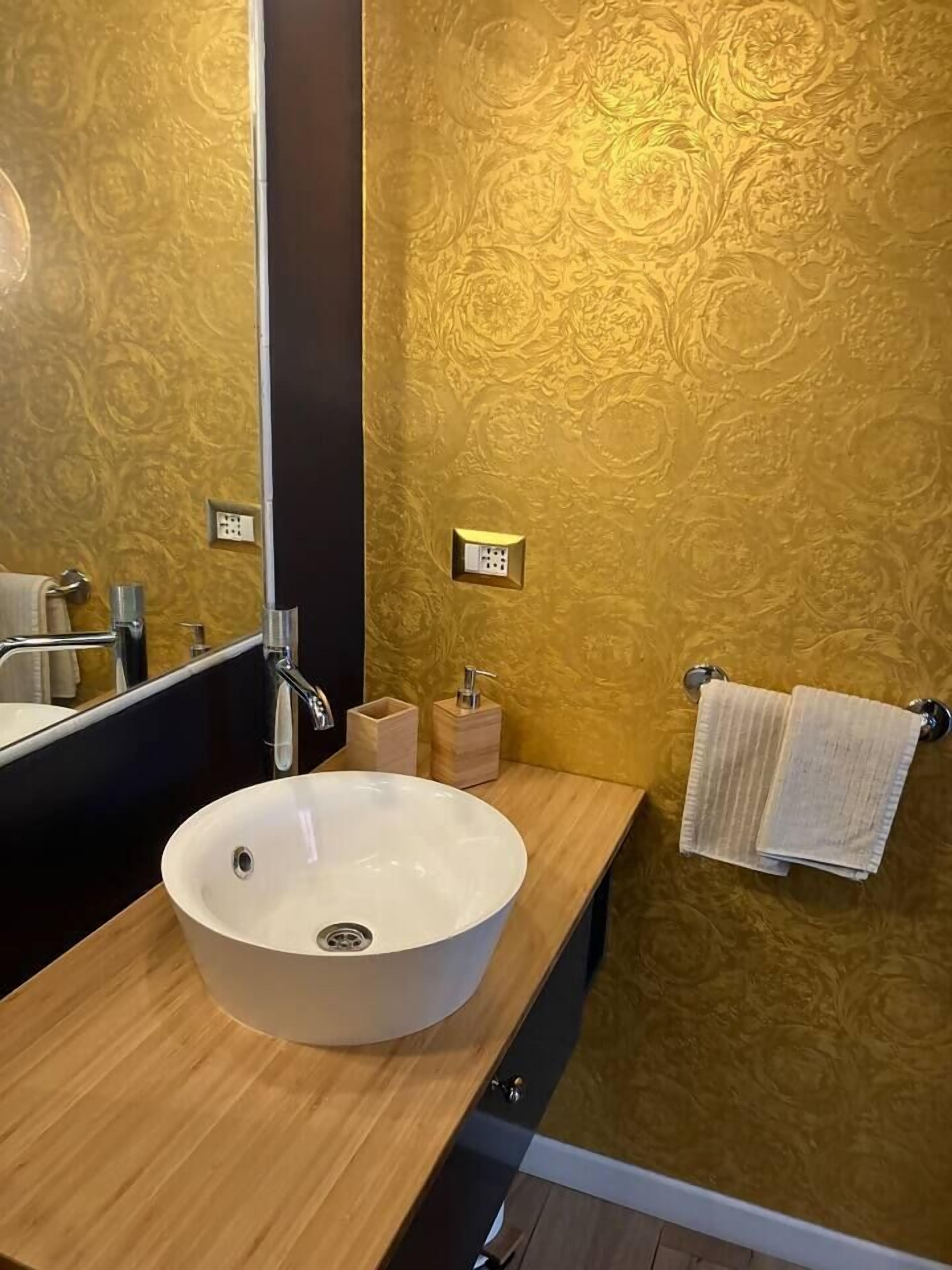 Une salle de bain avec un lavabo rond blanc, un miroir et un porte-serviettes.