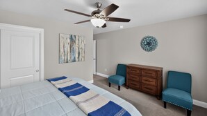A bedroom with a bed, a ceiling fan, a dresser, two chairs, and a wall decoration. - Casa Encantada | Pool, Pickleball, Near Zion (Washington)