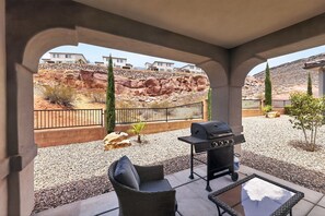 A covered patio with a barbecue grill, outdoor furniture, and a view of a rocky landscape. - Casa Encantada | Pool, Pickleball, Near Zion (Washington)