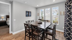 A dining area with a rectangular table and six chairs, a ceiling with recessed lighting, and a window with a view of a mountainous landscape. - Casa Encantada | Pool, Pickleball, Near Zion (Washington)