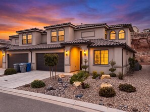 A two-story house with a garage, a driveway, and a landscaped front yard with rocks and shrubs. - Casa Encantada | Pool, Pickleball, Near Zion (Washington)