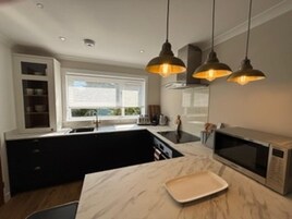 Una cocina moderna con iluminación colgante, microondas y encimera de mármol.