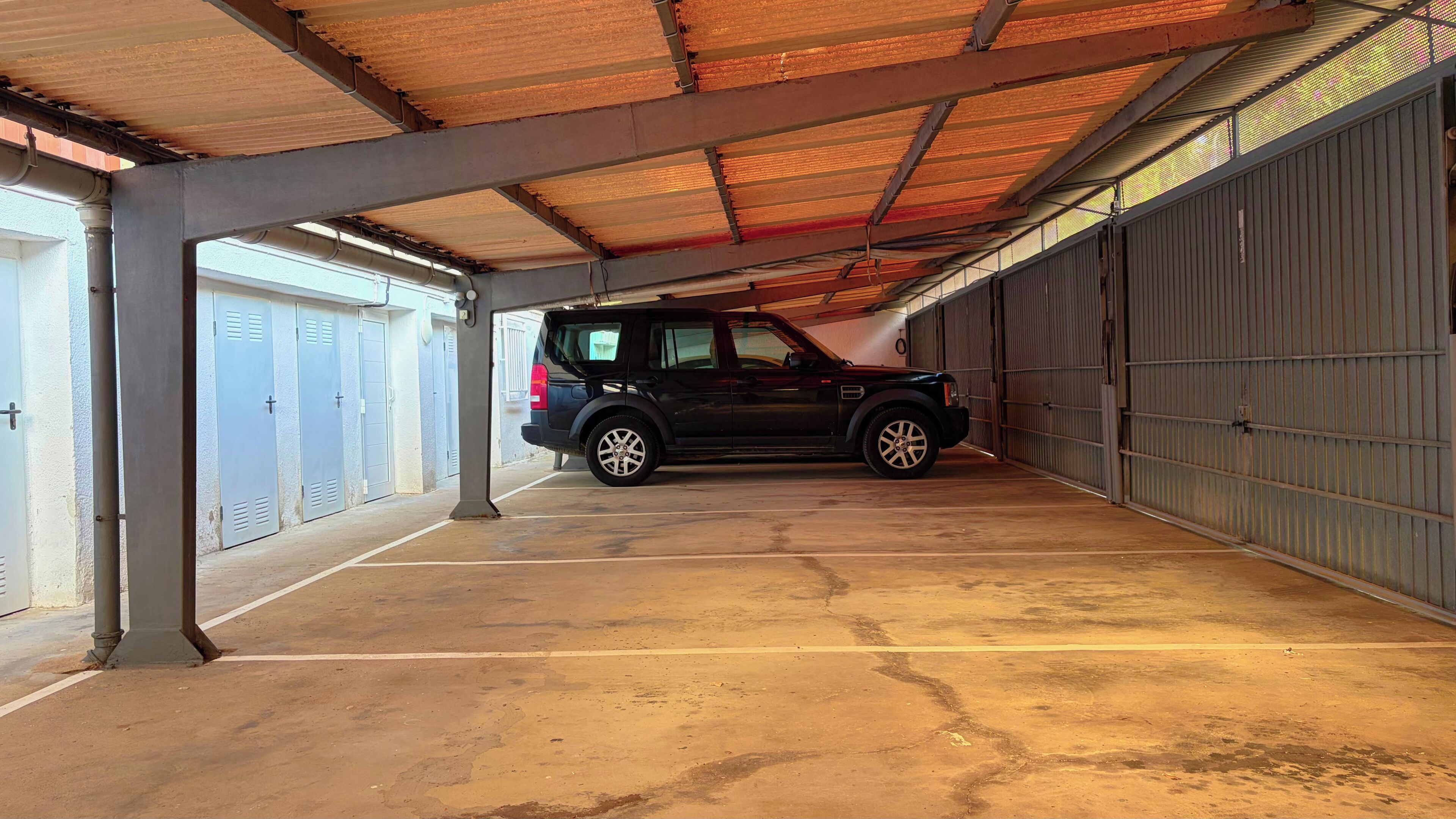 A covered parking area with a vehicle parked inside.