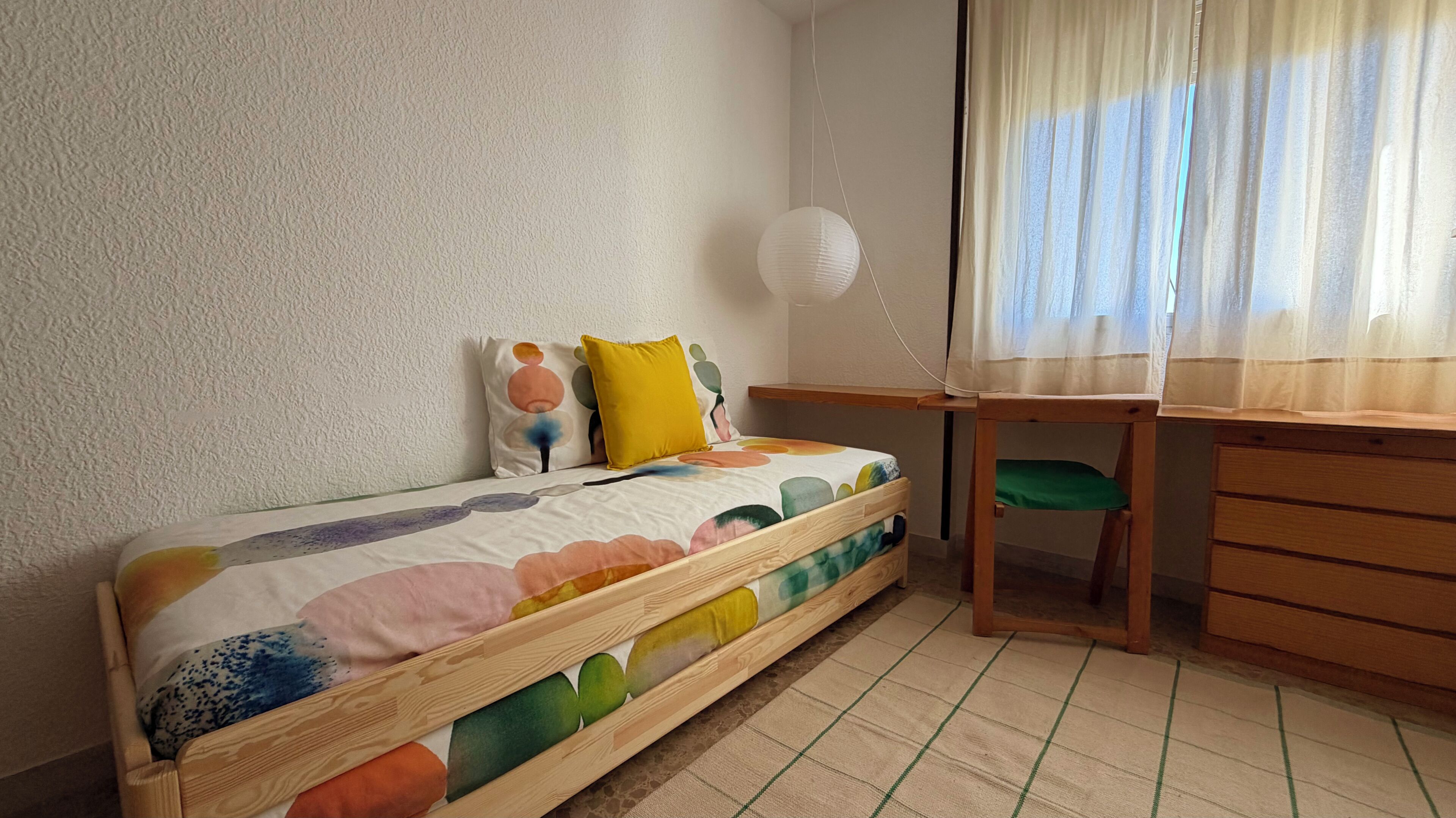 Una habitación pequeña y acogedora con una cama individual, un escritorio y una silla.