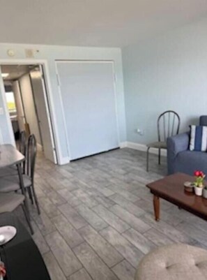 A living room with a dining table, chairs, a sofa, and a coffee table. - At the heart of Myrtle Beach Oceanfront Condo (Myrtle Beach)
