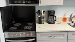 A kitchen with a stove, oven, microwave, and white cabinets. - At the heart of Myrtle Beach Oceanfront Condo (Myrtle Beach)