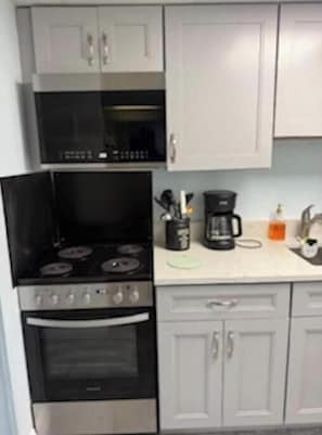A kitchen with a stove, oven, microwave, and white cabinets. - At the heart of Myrtle Beach Oceanfront Condo (Myrtle Beach)
