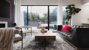 A modern living room with a sofa, armchair, and coffee table, large windows, and a plant. - South Congress - Walk to SXSW, Downtown, ACL (Austin)