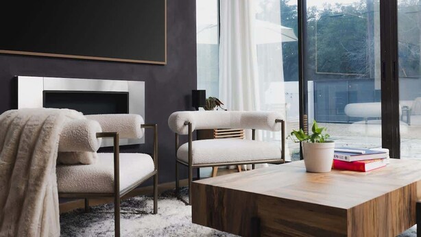 A modern living room with a fireplace, two armchairs, a coffee table, and a view of the outdoors. - South Congress - Walk to SXSW, Downtown, ACL (Austin)