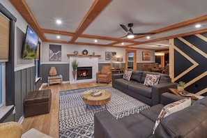 Ein modernes Wohnzimmer mit Kamin, Sofas, einem Couchtisch und Deckenventilator.