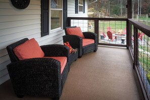 Eine überdachte Veranda mit Korbmöbeln und einem Feuerkorb.