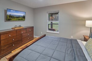 Een slaapkamer met een bed, een kaptafel, een raam en uitzicht op het landschap.