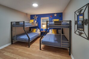 Ein Zimmer mit zwei Etagenbetten, Holzboden, einem Fenster mit Blick und Sternen an der Wand.