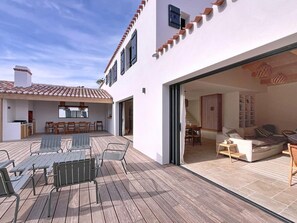 A modern house with a patio, a dining area, and a living room with a sofa and coffee table. - Stunning new home in La Clere, Noirmoutier, with 6 bedrooms, 100 meters from the beach (Noirmoutier-en-l'Île)