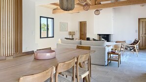 A spacious living area with a wooden dining table, a sofa, a fireplace, and a hanging light fixture. - Stunning new home in La Clere, Noirmoutier, with 6 bedrooms, 100 meters from the beach (Noirmoutier-en-l'Île)
