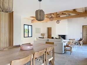 A spacious living area with a wooden dining table, a sofa, a fireplace, and a hanging light fixture. - Stunning new home in La Clere, Noirmoutier, with 6 bedrooms, 100 meters from the beach (Noirmoutier-en-l'Île)