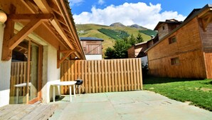 Una cabaña de madera con un patio, una valla de madera y vistas a la montaña.