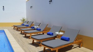 Una piscina al aire libre, tumbonas