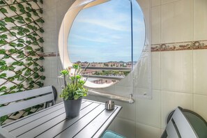 A balcony with a view of a cityscape, a potted plant, a metal cup, and a bench. - LXR Jazmines 2-Bedroom, Downtown (Fuengirola)
