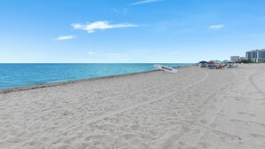 A beach with a lifeguard stand, umbrellas, and buildings in the background. - 3BR Home Near Fort Lauderdale Beach | Sleeps 5 (Fort Lauderdale)
