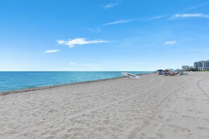 A beach with a lifeguard stand, umbrellas, and buildings in the background. - 3BR Home Near Fort Lauderdale Beach | Sleeps 5 (Fort Lauderdale)