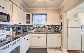 A modern kitchen with white cabinets, a microwave, a stove, a sink, and a refrigerator. - 3BR Home Near Fort Lauderdale Beach | Sleeps 5 (Fort Lauderdale)