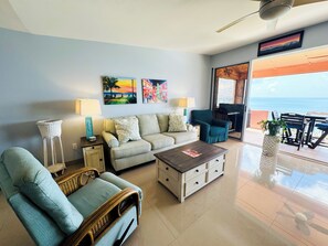 Ein Wohnzimmer mit Sofa, Sesseln, Couchtisch und Kunstwerk an der Wand.