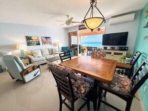 A modern living room with a dining area, a ceiling fan, a TV, and a view of the ocean. - The Lookout-New Booking Discount--Caribbean views, pool, generator. (Christiansted)