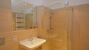Un bagno con box doccia in vetro, lavandino e specchio.