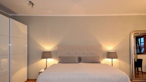 Una camera da letto con un letto grande, due lampade ai comodini, un armadio e uno specchio.